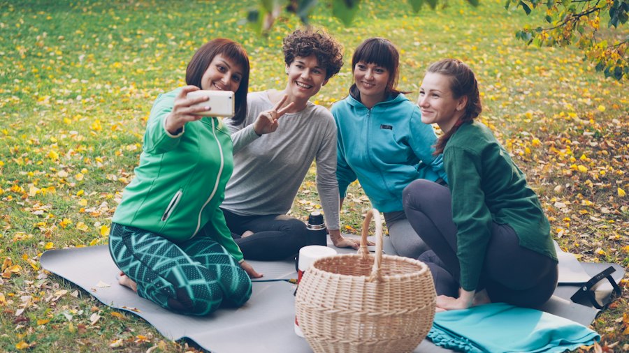 Four women taking a selfie together on a picnic blanket